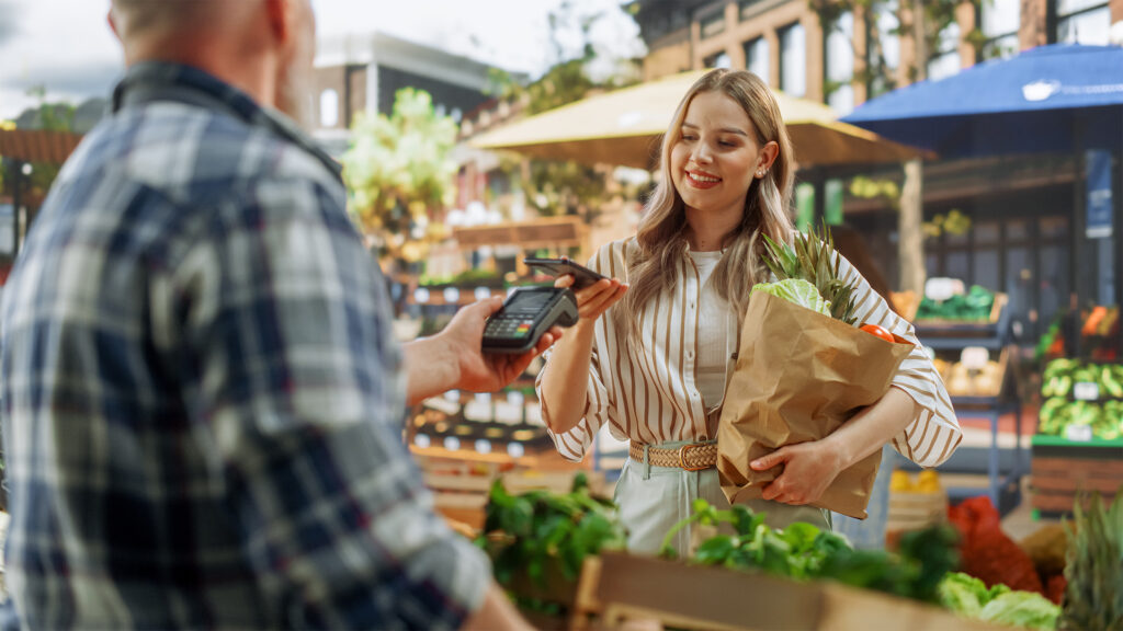 Woman tapping to pay with her phone at a farmers market