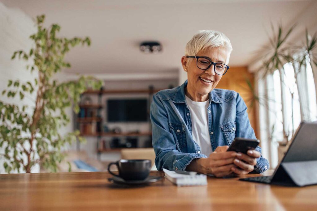 Happy mature woman, having piece of mind sitting at her home on her phone